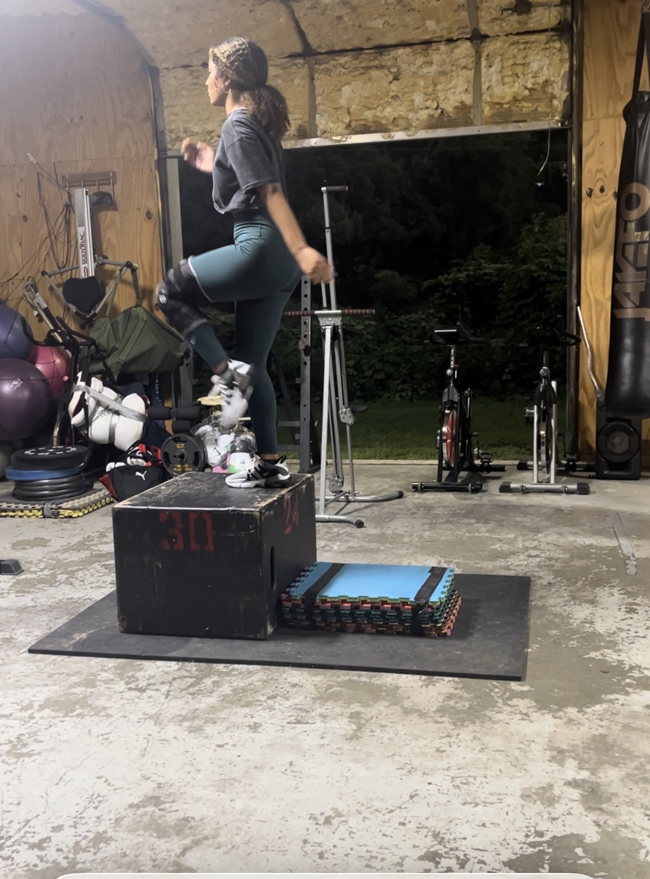 Athlete doing weighted step-ups and box jumps in the garage gym