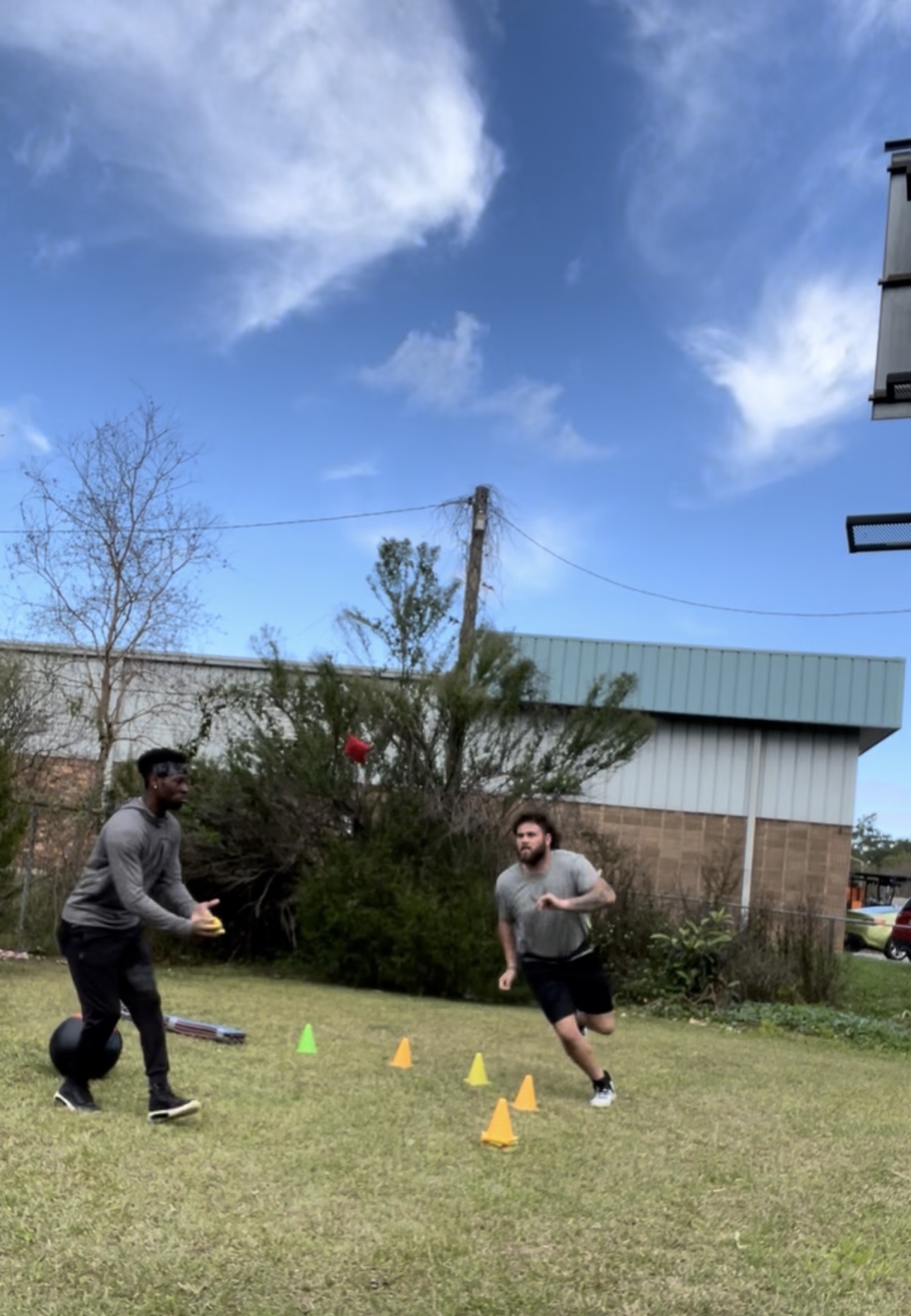Two athletes running reactive cone and agility drills outdoors