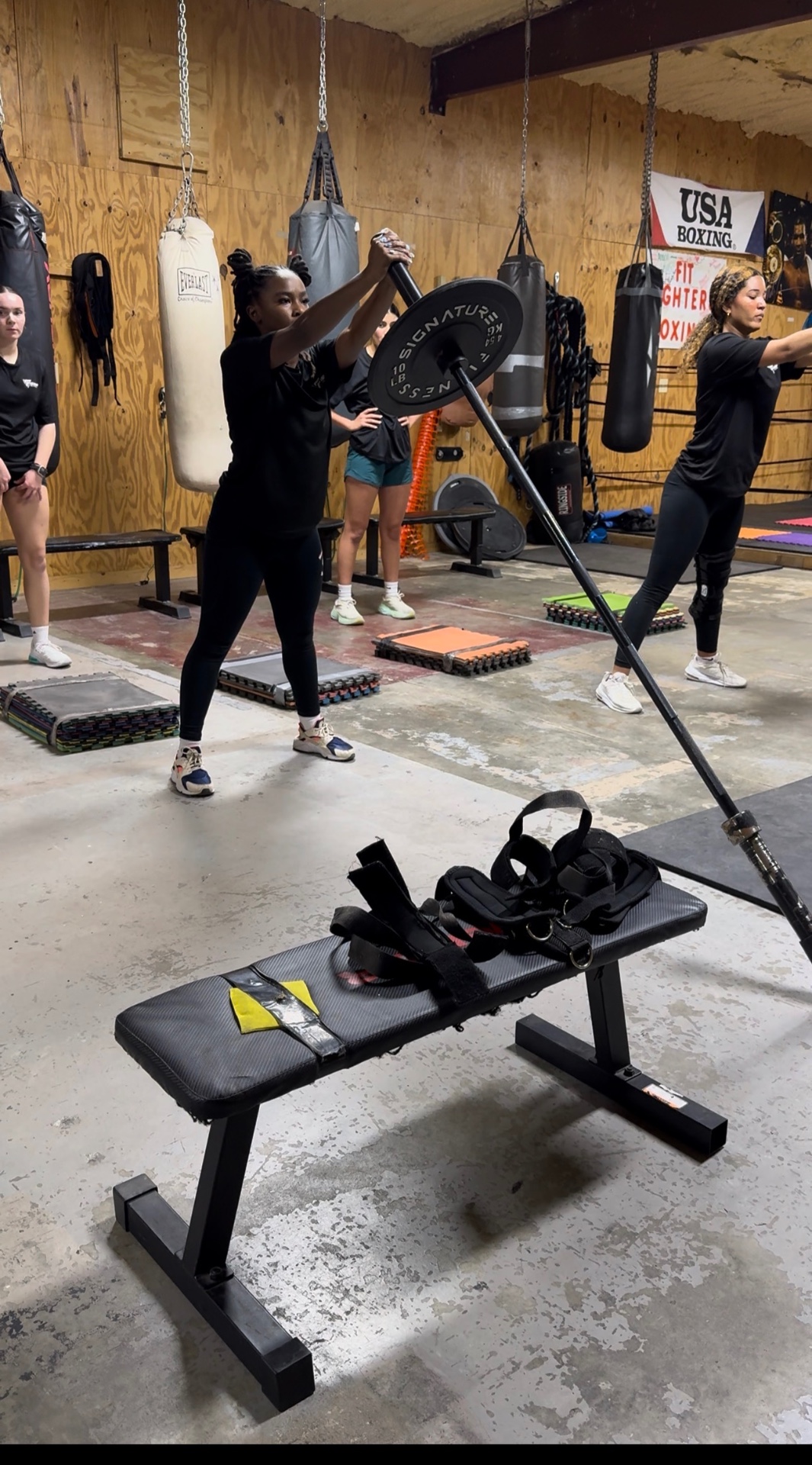 Athlete doing seated barbell press with a coach spotting