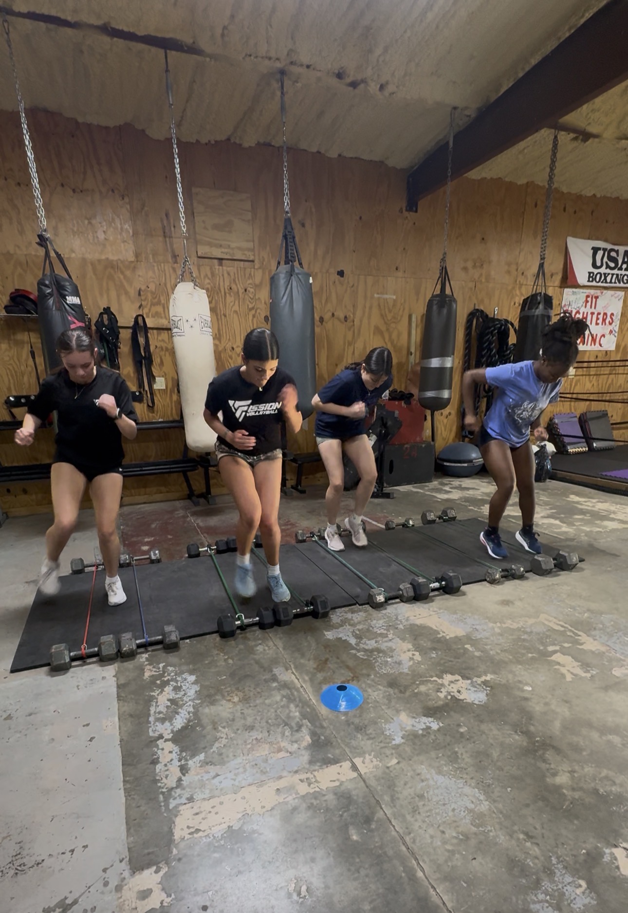 Volleyball athletes training footwork over dumbbell ladders