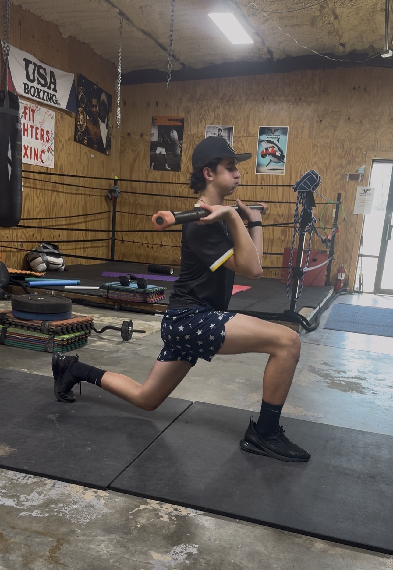 Young athlete doing weighted lunges with a training bar