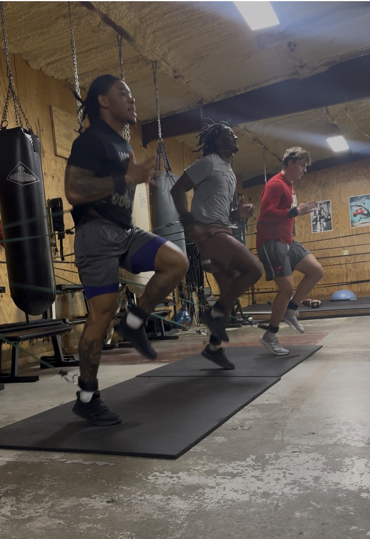 Athletes running high-knee drills together on the mat