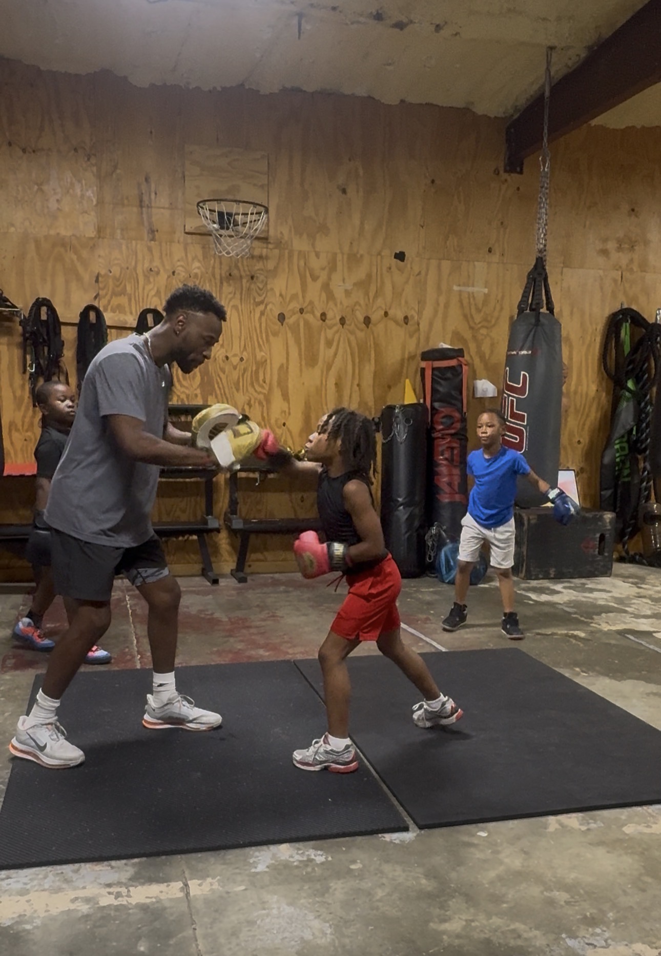 Coach Dom holding mitts for a young Fit Fighters boxer in training