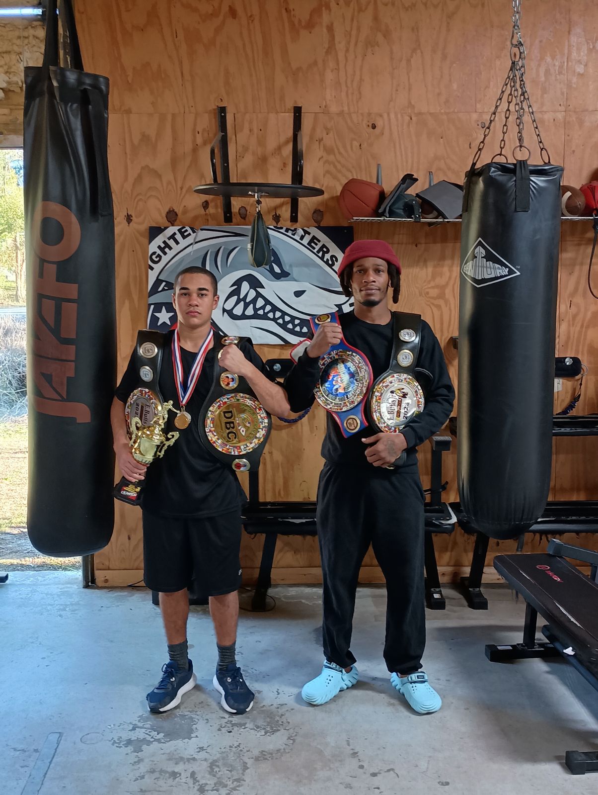 Two Fit Fighters amateur champions with belts and trophies
